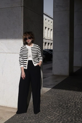 a lady in a white top, a black and white striped cardigan and a pair of black wide leg pants
